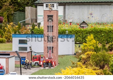 Closeup of firemen and a large ladder at a model village in England