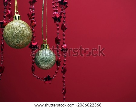 Golden Christmas balls and garland on a red background. Christmas mood. Copy space