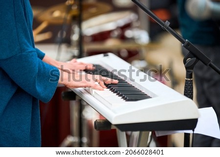 Musician woman playing on white synthesizer keyboard piano keys, female hands on synthesizer, close up. Musician playing synthesizer on concert stage, professional playing on synth piano Royalty-Free Stock Photo #2066028401