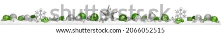 Christmas border or banner with stars and baubles arranged in a row on snow, silver and green, extra wide and isolated on white background