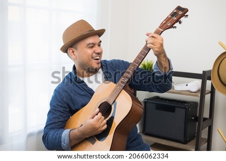 Lifestyle concept. Young asian musician playing guitar in living room at home on this weekend. Relaxing with song and music. Asian man having fun playing acoustic guitar Royalty-Free Stock Photo #2066062334