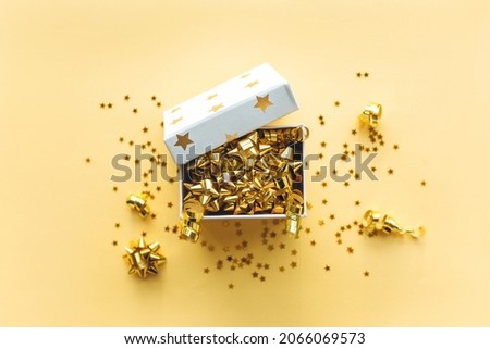 Open gift white box with tinsel and confetti on a gold background. Celebrating Christmas or New Years or winning a prize or a promotion or other holiday concept. Flat lay, top view Royalty-Free Stock Photo #2066069573