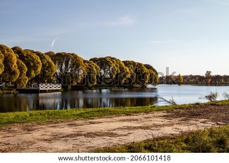 Autumn colors background. Wooden pier and autumn trees over the lake. Panoramic morning view of pond.