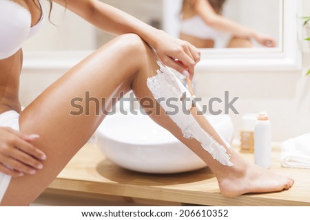 Close up of woman shaving legs in bathroom Royalty-Free Stock Photo #206610352