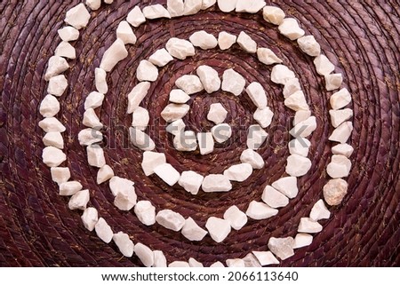Spiral Life Symbol written with white stones over a rustic purple texture