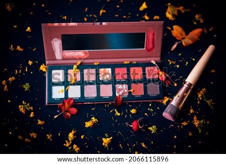 Professional cosmetics make up products and yellow flowers in autumn concept on dark background.