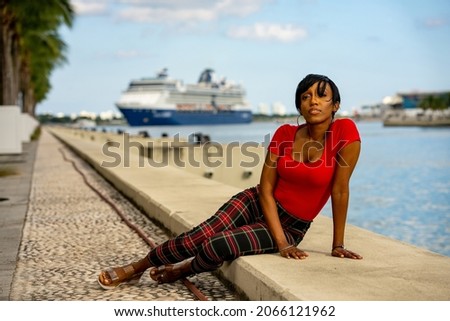 Woman sitting by the bay with cruise ship in background