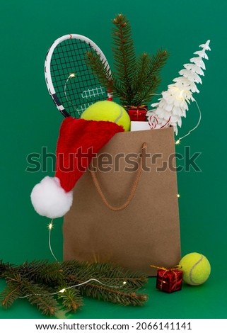 Christmas festive card for tennis players and lovers . in a gift bag a tennis racket, a yellow ball, a gift, a santa hat and fir tree.