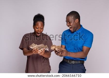 young african man and woman looking surprised and excited holding a lot of money Royalty-Free Stock Photo #2066166710