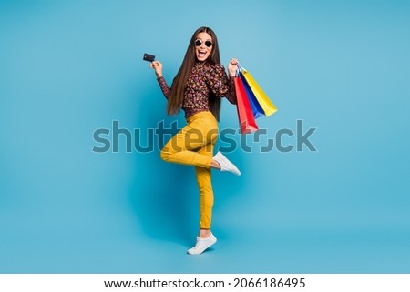 Full size photo of young attractive excited happy smiling cheerful woman hold bags show credit card isolated on blue color background