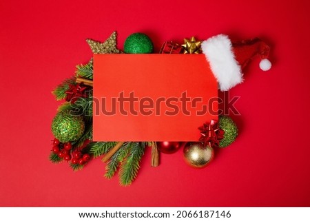 frame of Christmas tree branches and decorations with blank card and space for text red background. Top view. Xmas and New year concept. High quality photo