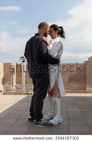 Married lovers couple hugging on tower terrace celebrating relationship anniversary enjoying beautiful metropolitan city view. Landscape with urban skyscraper rooftop and aerial view