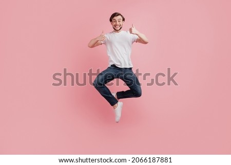 Full size photo of young happy excited smiling positive man jump show thumb-up like cool advert isolated on pink color background