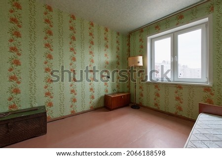Example of Old Soviet Russian poor interior in Leningrad project House. Aged  sideboard, table, chairs, bed. Shabby floor. Tattered wallpaper on the wall. Apartment of pensioners. Selective focus. Royalty-Free Stock Photo #2066188598
