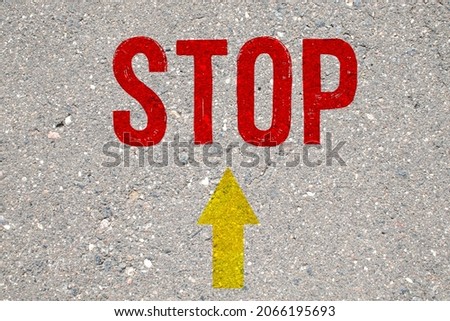 bright white road sign uppercase capital letter STOP and direction arrows on new textured black asphalt