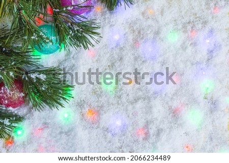 Festive New Year background artificial snow and colored lights with fir branches place for text.