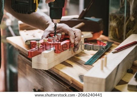 carpenter use drill bit and centering dowel jig tool to make strong joints . woodworking concept.selective focus. Royalty-Free Stock Photo #2066240441