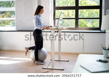 Woman Using Adjustable Height Standing Desk In Office For Good Posture Royalty-Free Stock Photo #2066251757