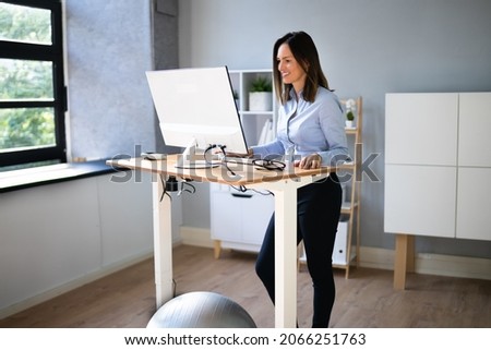 Woman Using Adjustable Height Standing Desk In Office For Good Posture Royalty-Free Stock Photo #2066251763