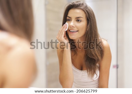 Beautiful brunette woman removing makeup from her face Royalty-Free Stock Photo #206625799