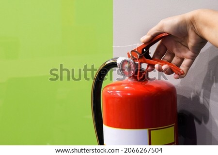 Closed-up fire extinguishers on wall, focus on the holder and meter.