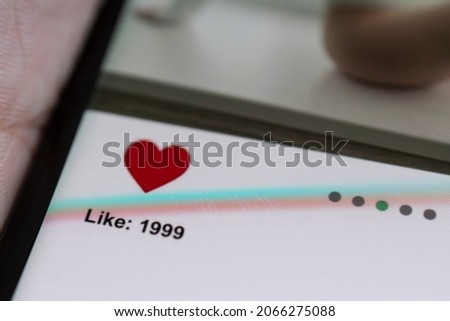 dependence on social networks concept. man looks through a news feed on a social network and puts likes in new posts of girls. All the graphics on the screen are made up.