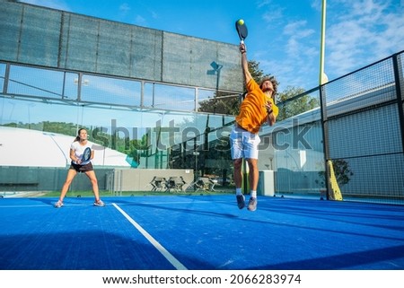 Mixed padel match in a blue grass padel court - 
Beautiful girl and handsome man playing padel outdoor Royalty-Free Stock Photo #2066283974
