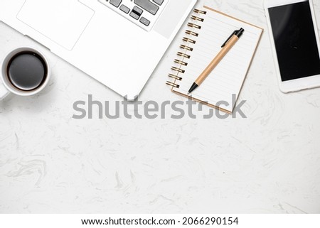 Top view office desk with keyboard, notebooks and coffee cup on marble background.