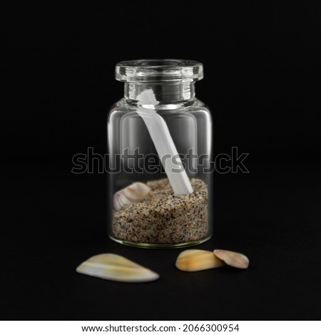 A little message in a bottle with some mini shells on a black background.