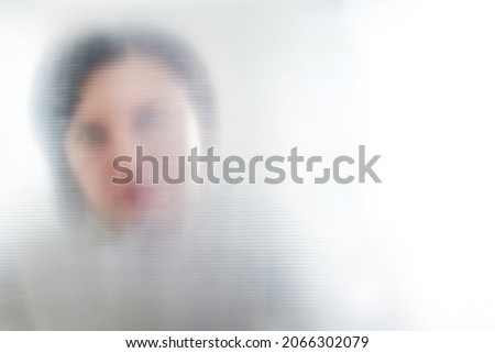 Silhouette of blurred lonely woman looking through transparent plastic