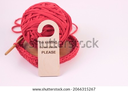 i'm knitting Do not disturb please sign on crocheted red box background.Wooden sign with knitting accessories on white, copy space.Female hobby, leisure or remote knitting work concept. 
 Royalty-Free Stock Photo #2066315267