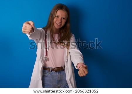 Young caucasian doctor woman wearing medical uniform and stethoscope over blue background imagine steering wheel helm rudder passing driving exam good mood fast speed