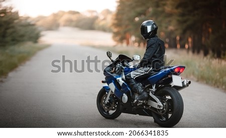 Biker in a protective suit with a helmet. Motorcyclist in helmet and leather jacket on the road on a sports motorcycle Royalty-Free Stock Photo #2066341835