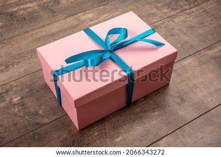 Pink gift tied with blue ribbon, on wooden rustic table. Valentine's Day or Christmas gift box presents. Christmas present, valentine day surprise, birthday concept. close up