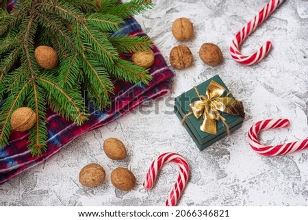 New Year's or Christmas composition of spruce green branches, red plaid, walnuts, gift and Christmas lollipops on a bright textural background. Flat lay, layout, frame, copy space