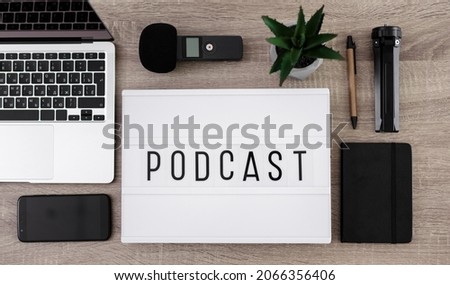 podcast and blogging concept - flat lay with lightbox with podcast word and equipment for audio content recording