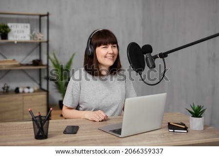 portrait of young woman streaming her audio podcast using microphone and laptop