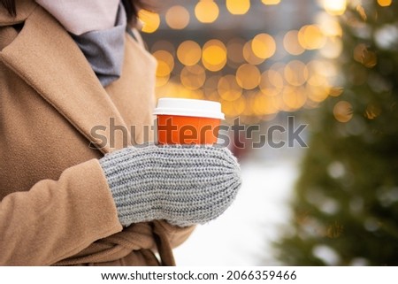 Close up of hands in mittens with cup of hot drink in wintertime