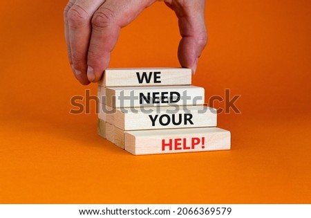 We need your help symbol. Wooden blocks with concept words 'We need your help'. Businessman hand. Beautiful orange background. Business, support and we need your help concept. Copy space.
