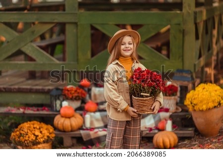 girl in a hat with autumn decor with pumpkins and flowers