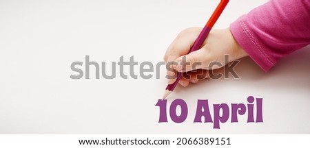 A child's hand writes 10 april in lilac pencil. Banner with copy space