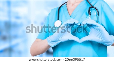 Doctor woman, hands in medical blue gloves forming a heart shape. We love you. Copy space. Awareness Poster. Royalty-Free Stock Photo #2066395517