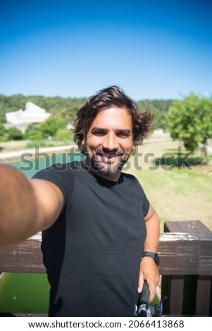 Handsome man taking selfie photo. Person in black t-shirt with bicycle picturing himself in park. Sport, disability concept