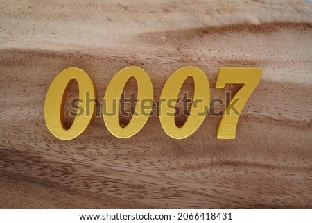Golden Arabic numerals 0007 on a dark brown to white wood grain background.