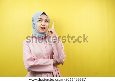 Beautiful young muslim woman getting idea, pointing up, isolated