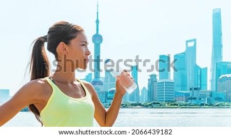 Healthy active lifestyle runner girl drinking water bottle at Shanghai skyline fitness Asian woman thirsty on summer heat. China panoramic banner. Health and sports.