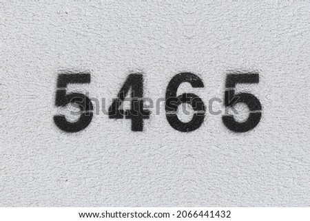 Black Number 5465 on the white wall. Spray paint. Number five thousand four hundred sixty five.