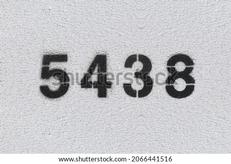 Black Number 5438 on the white wall. Spray paint. Number five thousand four hundred thirty eight.