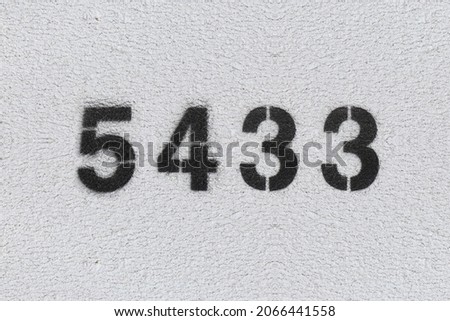 Black Number 5433 on the white wall. Spray paint. Number five thousand four hundred thirty three.