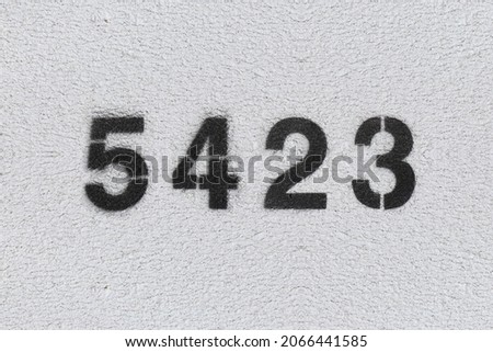 Black Number 5423 on the white wall. Spray paint. Number five thousand four hundred and twenty three.